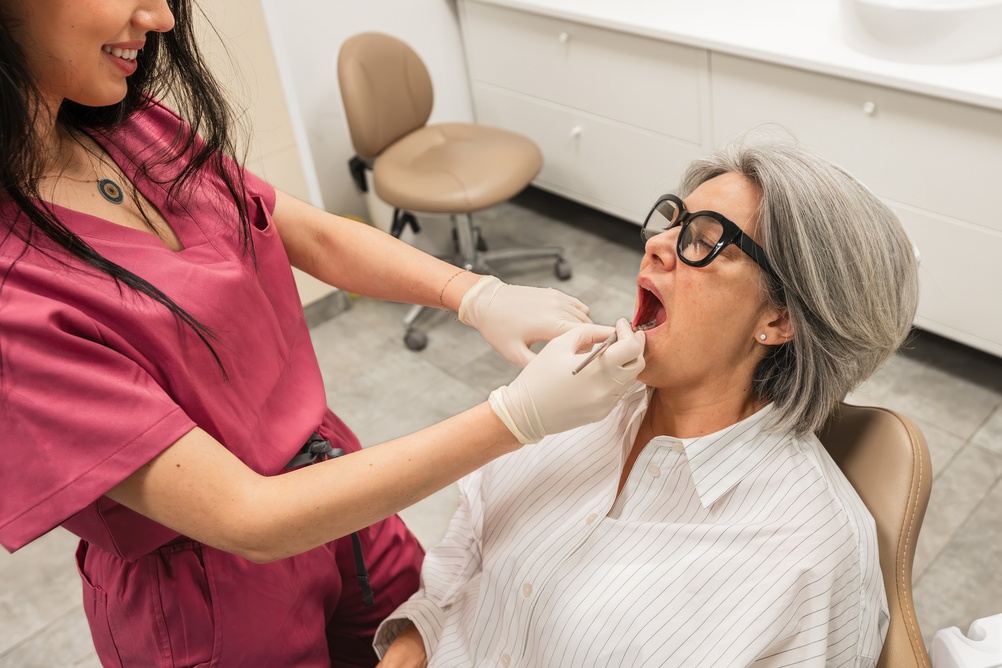 A modern office setting depicting a diverse surgical team, including a surgeon and a dental assistant, reviewing a 3D scan on a large monitor, with "Oral & Maxillofacial Surgery Near Me" subtly displayed as a title on the screen.