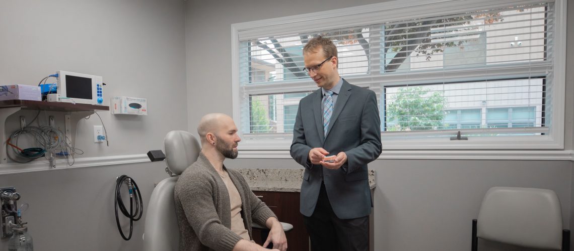 dr. billy laun talking with a patient while standing in one of his dental offices