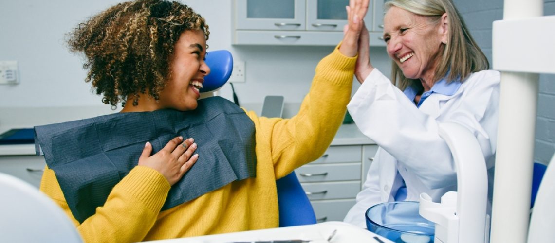 A split image of a full set of healthy, white teeth on the left, and a set of dentures on the right. The text on the image reads "Dental Implants vs Dentures"