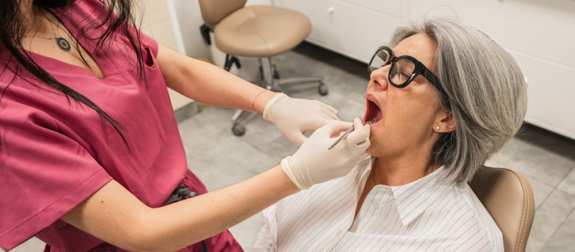 A modern office setting depicting a diverse surgical team, including a surgeon and a dental assistant, reviewing a 3D scan on a large monitor, with "Oral & Maxillofacial Surgery Near Me" subtly displayed as a title on the screen.